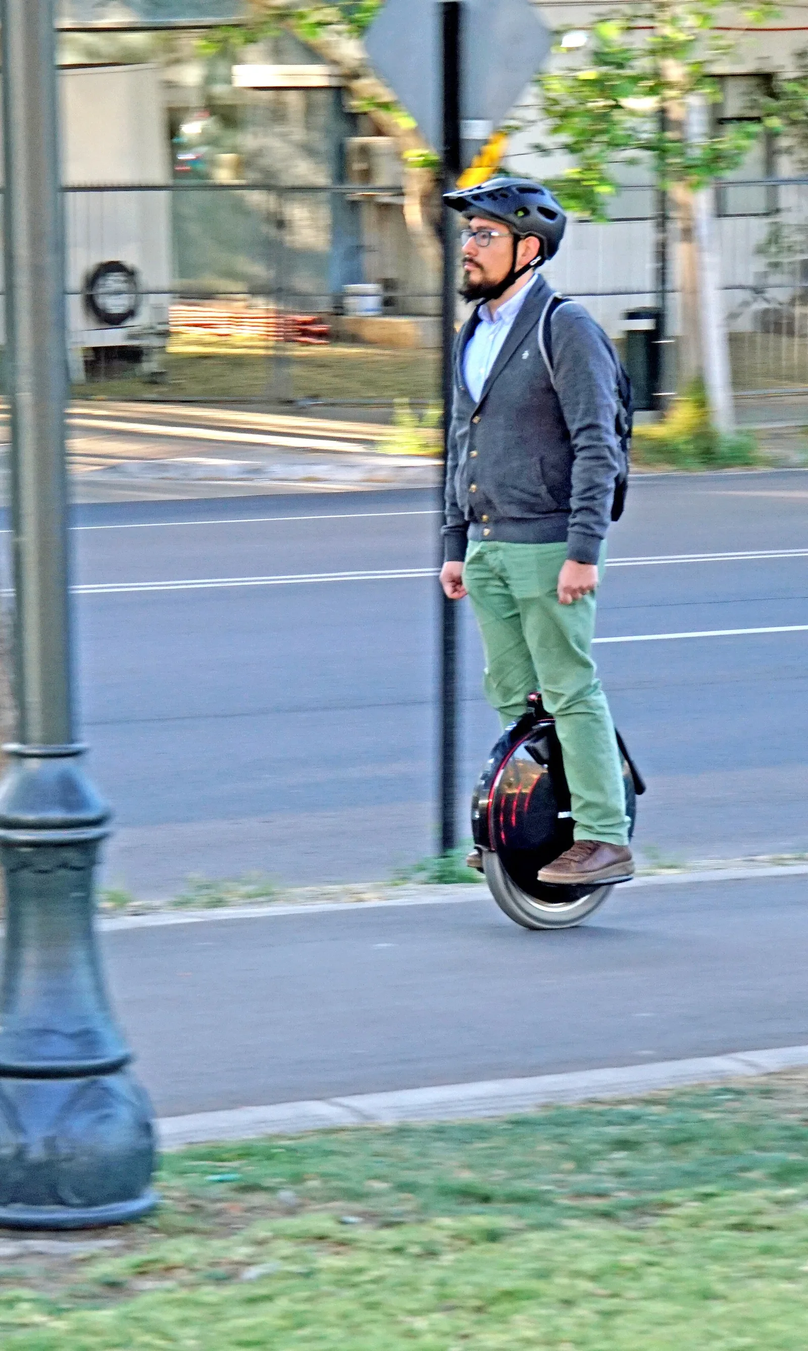 Rider casqué roulant en gyroroue sur un trottoir en bord de route arborée