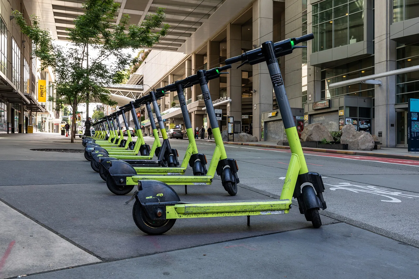 Longue file de trottinettes électriques vert citron alignées le long d'une rue de ville