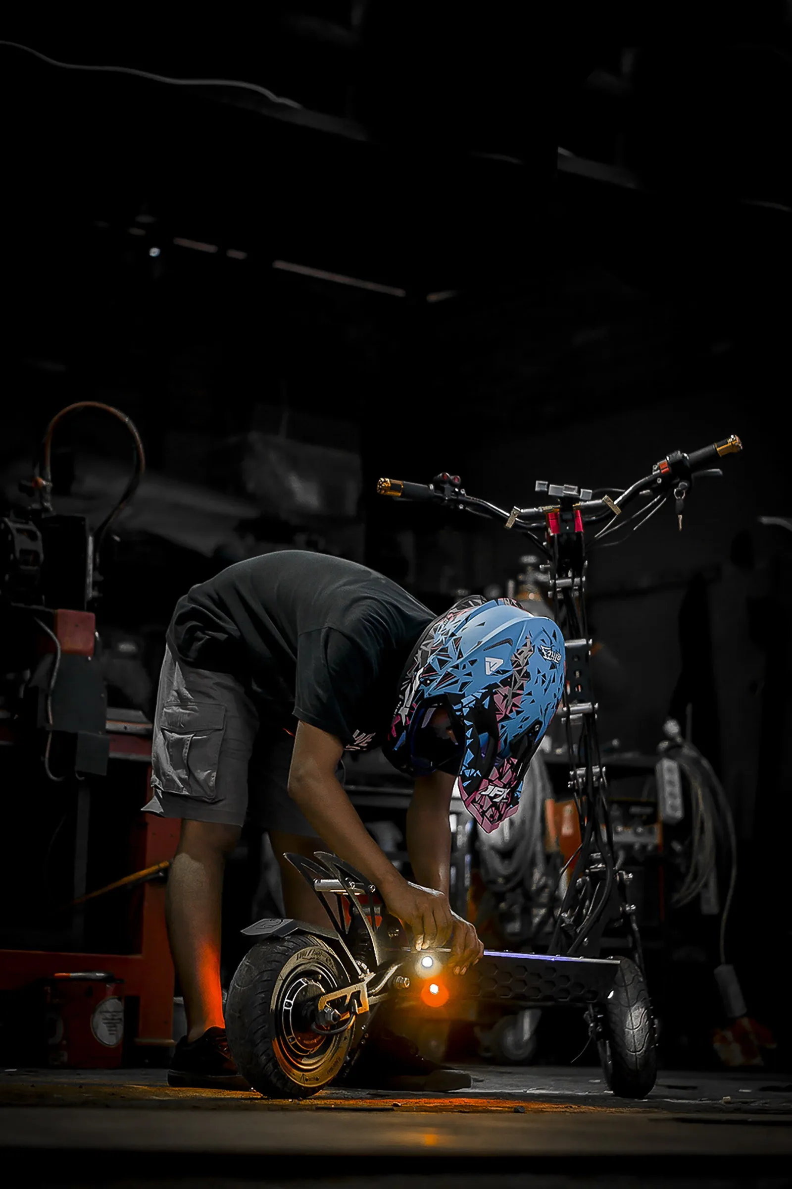 Rider casqué préparant une trottinette électrique tout-terrain à pneus crantés dans un atelier