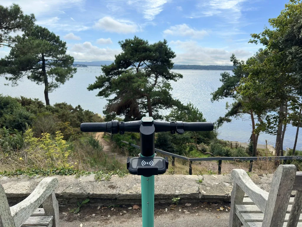 Guidon et potence d'une trottinette électrique devant un paysage de bord de mer