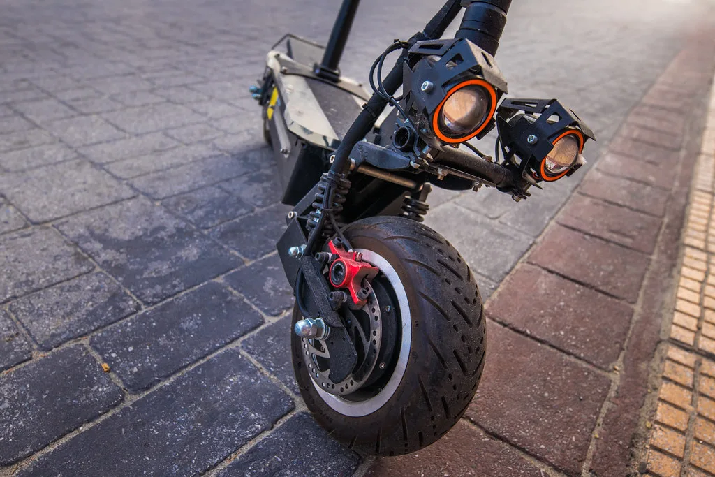 Gros plan sur le pneu avant d'une trottinette électrique puissante posée sur un pavage urbain