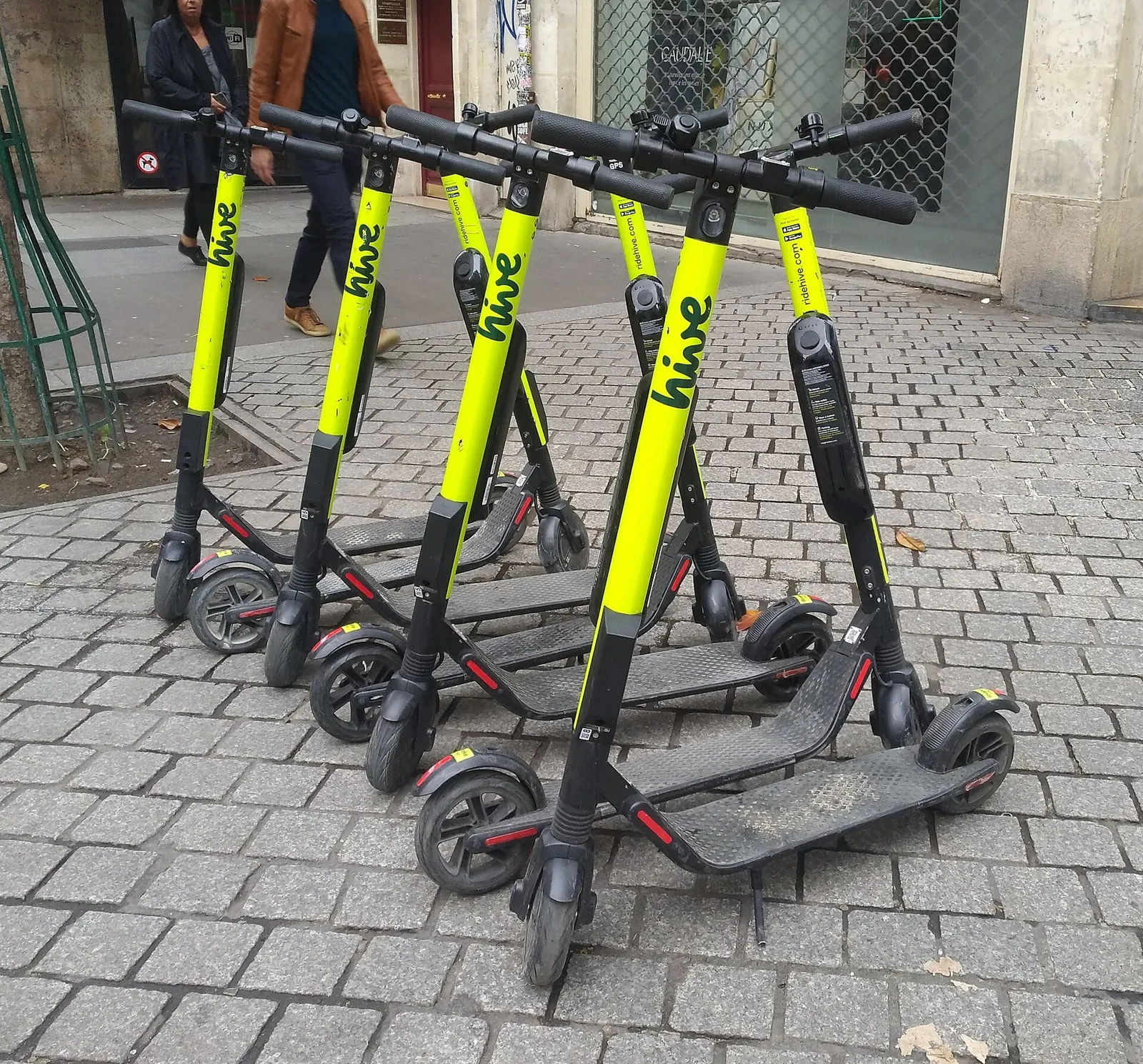 Plusieurs trottinettes électriques de location jaune fluo garées sur un pavé parisien
