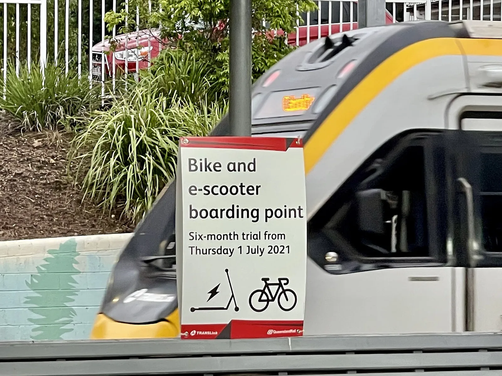 Panneau d'embarquement pour vélos et trottinettes électriques sur le quai d'une gare, devant un train